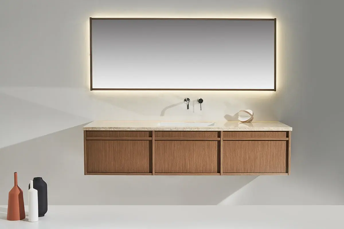Ensemble de salle de bain raffiné composé d’un meuble en chêne naturel 180 cm, surmonté d’un plan en marbre véritable Aman Cream Bloom. La vasque en céramique centrée est parfaitement encastrée dans le plan, offrant un rendu épuré et élégant. L’ensemble est complété par un miroir large (180x70 cm) avec cadre bois et rétro-éclairage LED intégré pour une ambiance chaleureuse et sophistiquée.