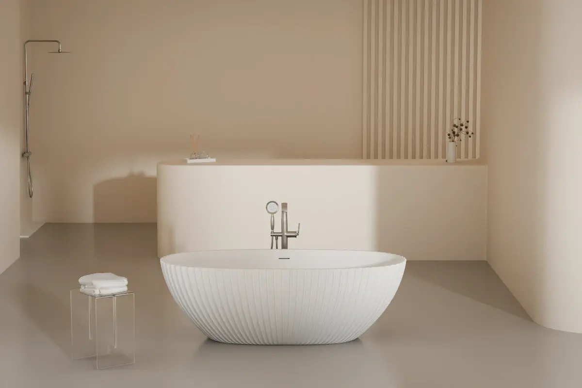 Baignoire îlot cannelée en solid surface blanc mat, forme ovale avec lignes verticales, posée devant un mur beige texturé avec robinetterie sur pied.