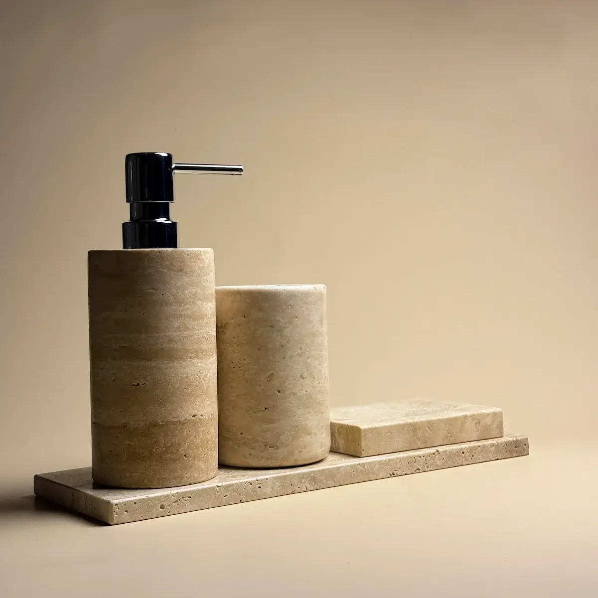 Ensemble d'accessoires salle de bain Yilstone en travertin beige rond avec distributeur à pompe chromée, pot, porte-savon et plateau.