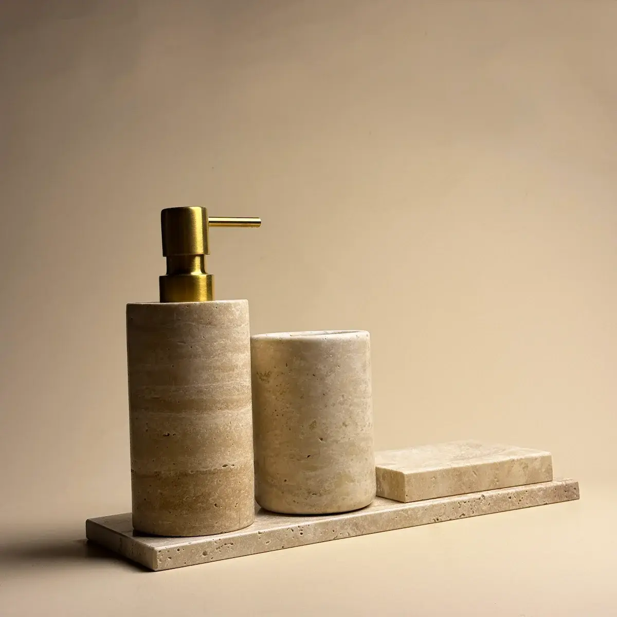 Ensemble d'accessoires salle de bain Yilstone en travertin beige rond avec distributeur à pompe chromée, pot, porte-savon et plateau.